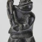 Carving of kneeling Inuk eating fish