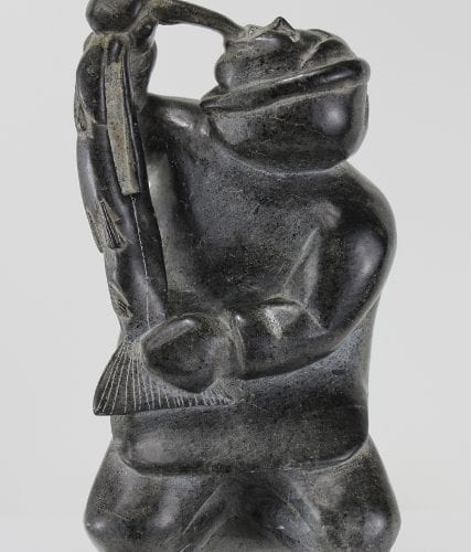 Carving of kneeling Inuk eating fish