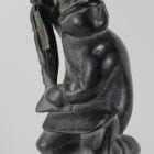 Carving of kneeling Inuk eating fish