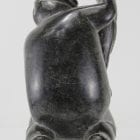 Carving of kneeling Inuk eating fish