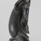 Carving of kneeling Inuk eating fish