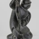 Carving of kneeling Inuk eating fish