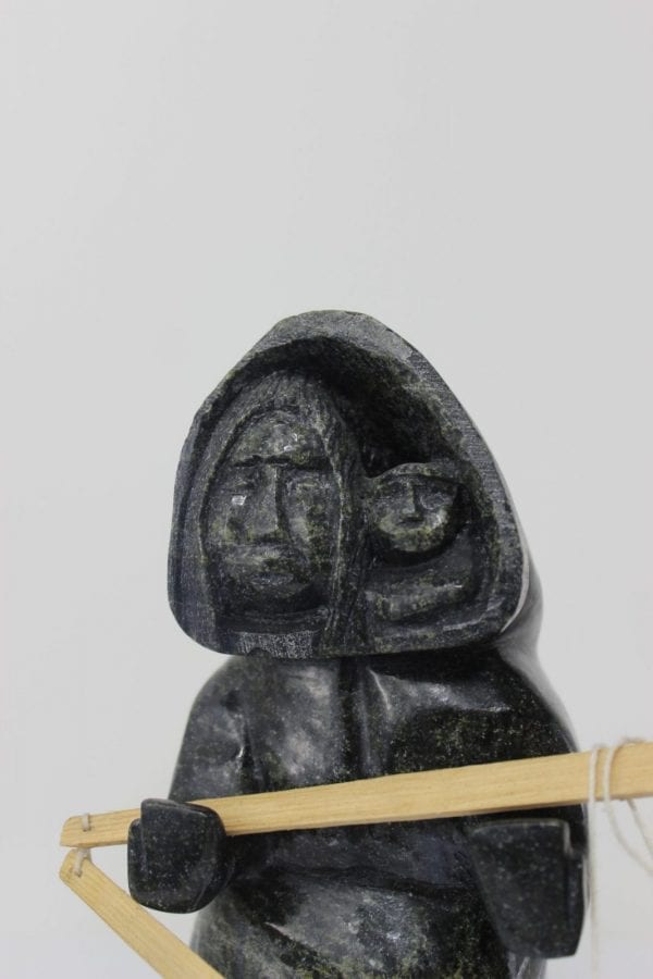 Drying skin, a three piece carving by Mosesee Pootoogook